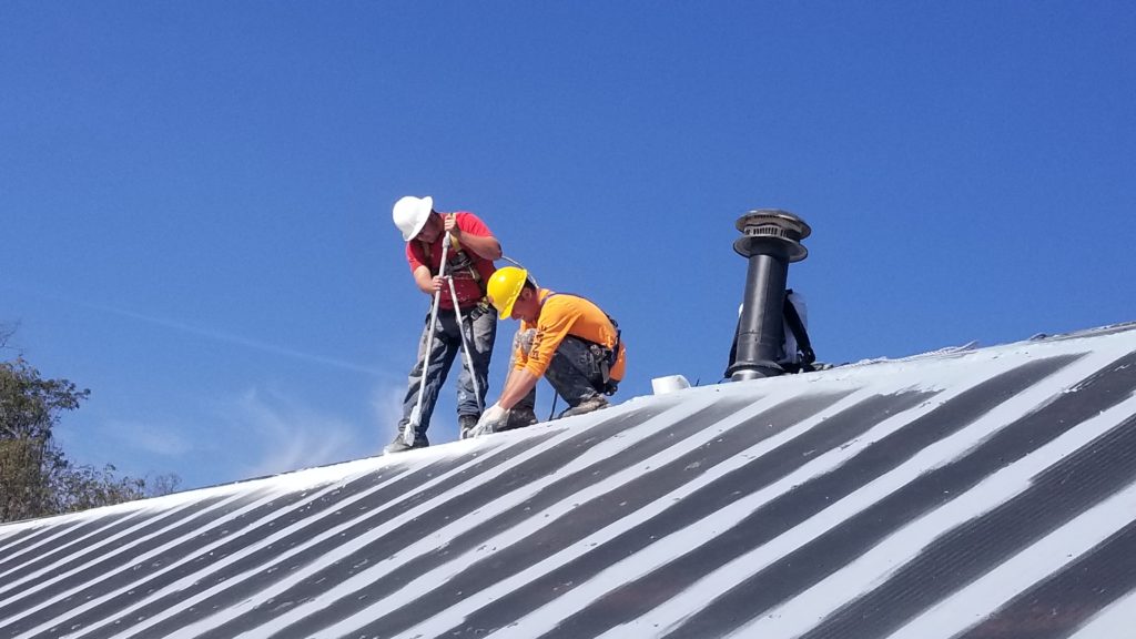 2 roofing technicians prepping roof for repair